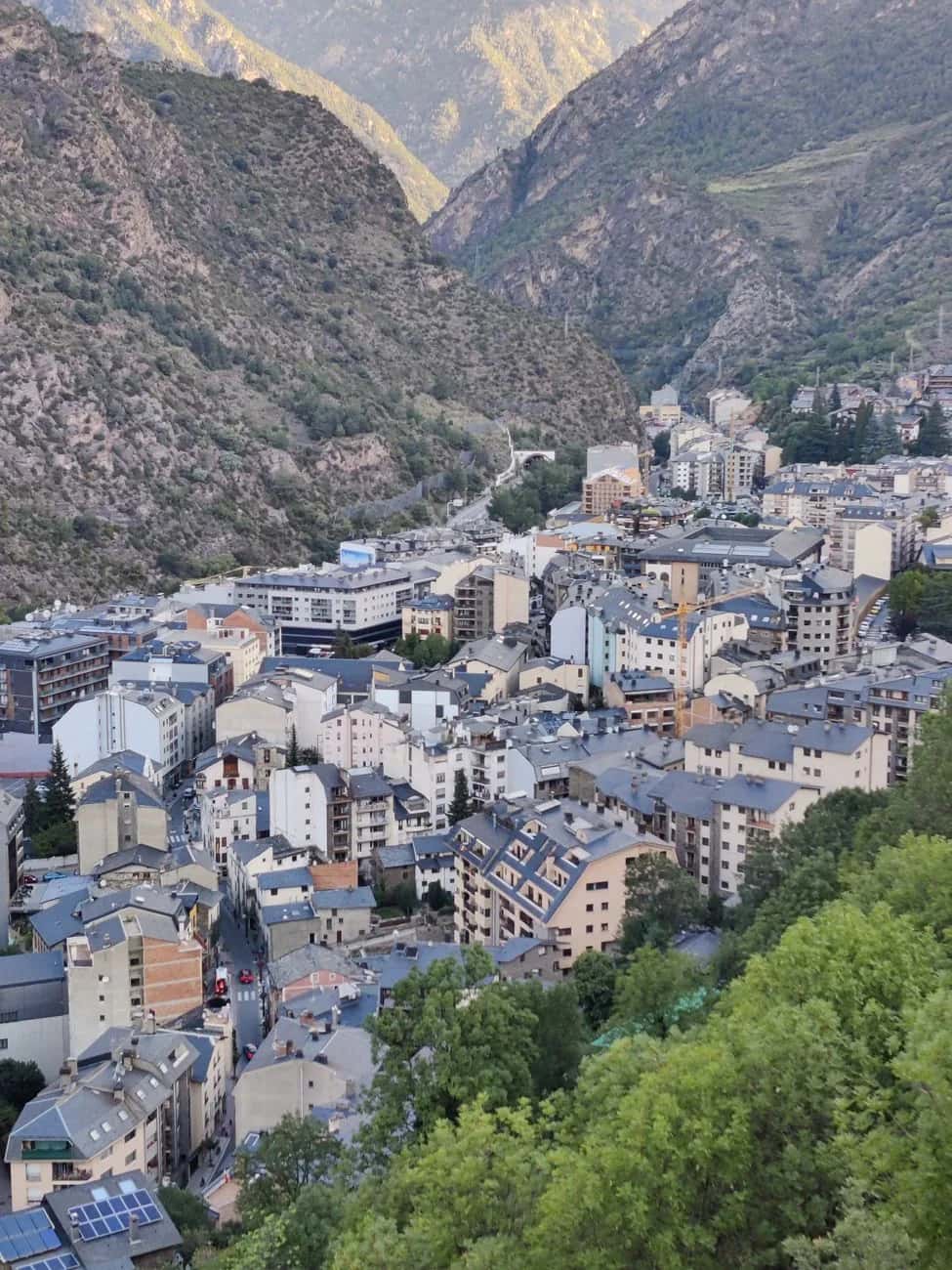 Andorra la Vella vue depuis les hauteurs, ses immeubles serrés dans le fond de vallée entre deux versants boisés