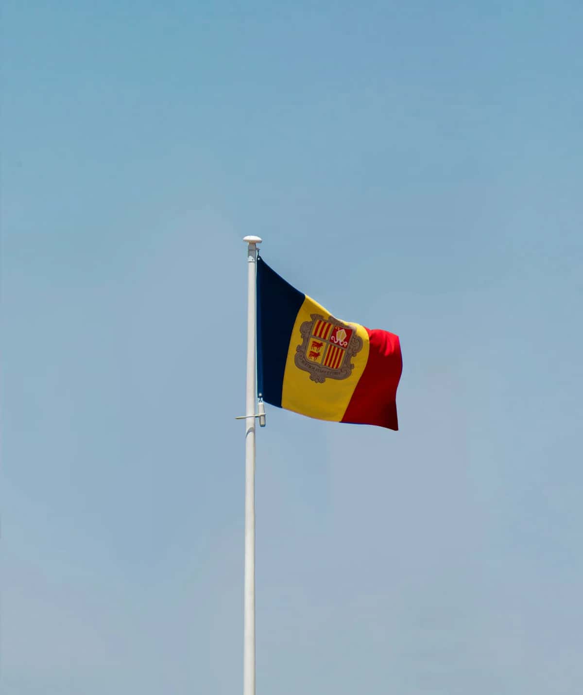 Le drapeau andorran déployé sur sa hampe, ses trois bandes bleue, jaune et rouge avec les armoiries au centre