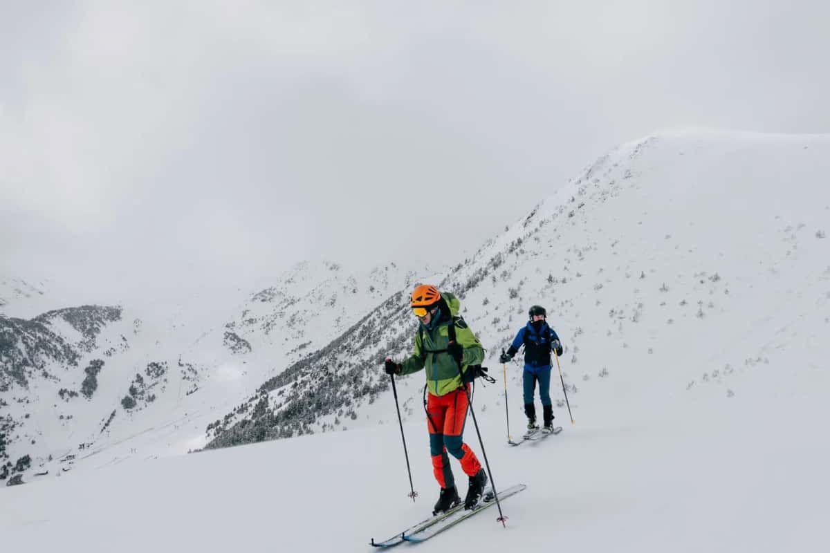 Deux skieurs de randonnée progressant au-dessus d'un domaine skiable andorran enneigé