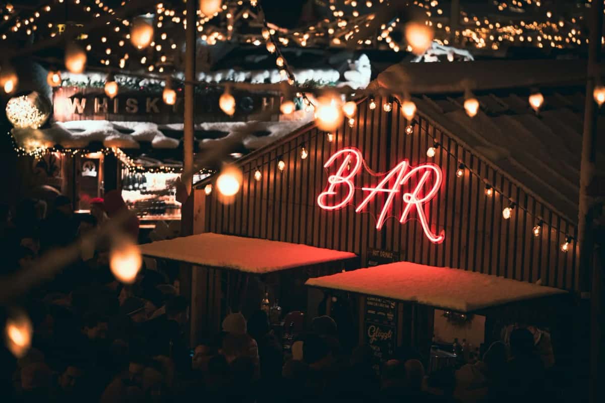 Bar en bois éclairé le soir, enseigne lumineuse et guirlandes