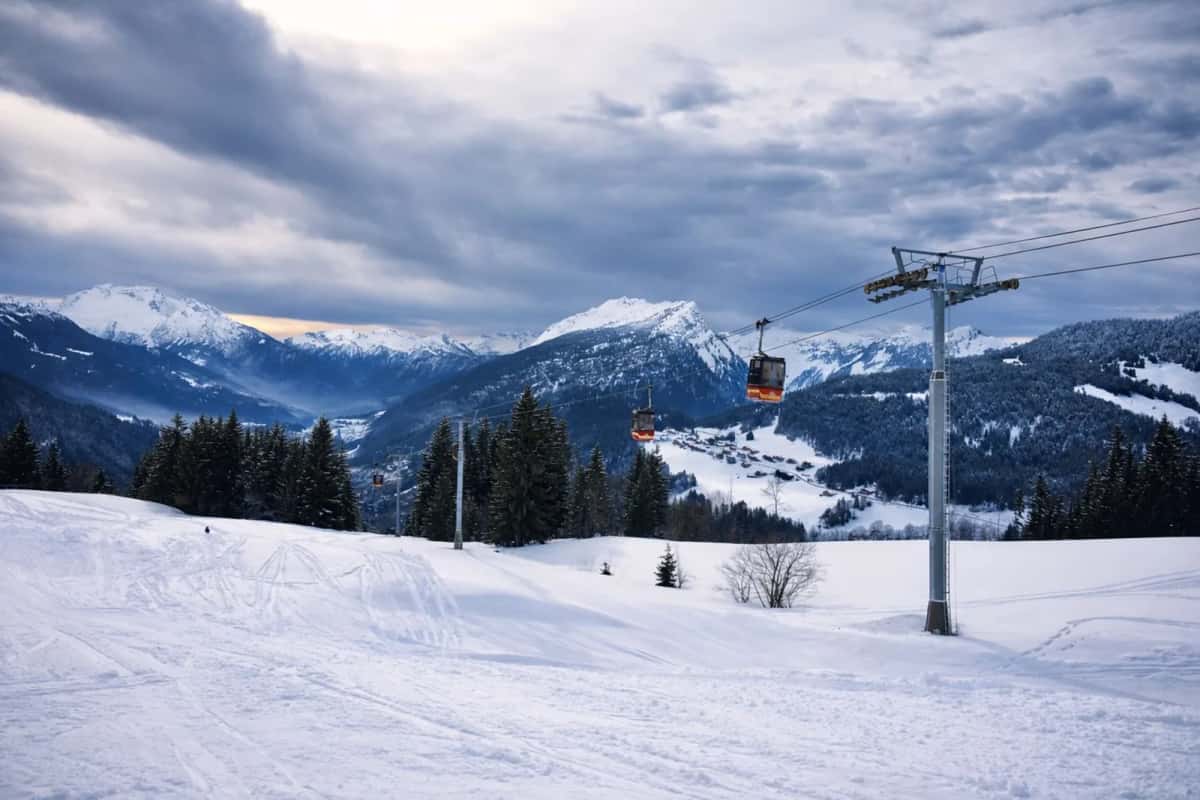 Télécabine au-dessus d'un domaine skiable enneigé, montagnes en arrière-plan