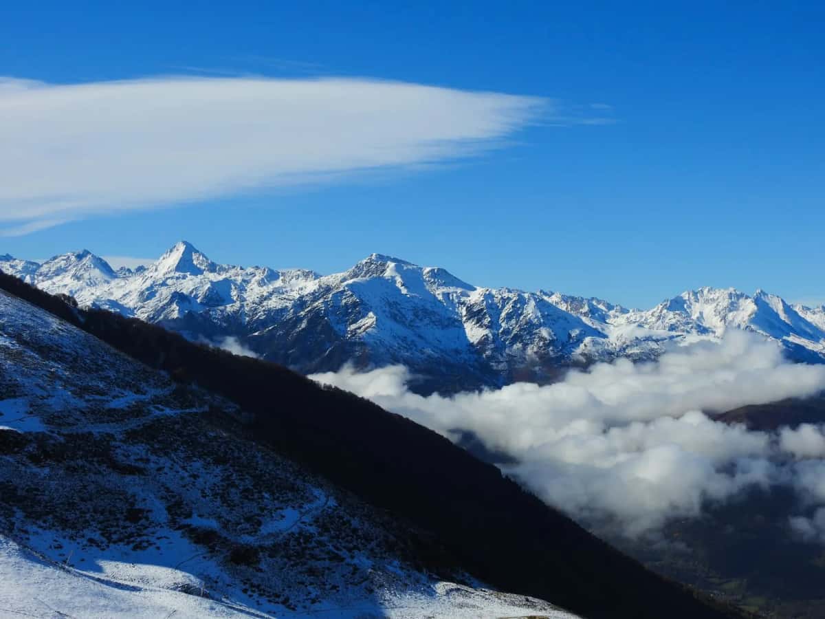 Sommets enneigés des Pyrénées émergeant d'une mer de nuages qui remplit la vallée
