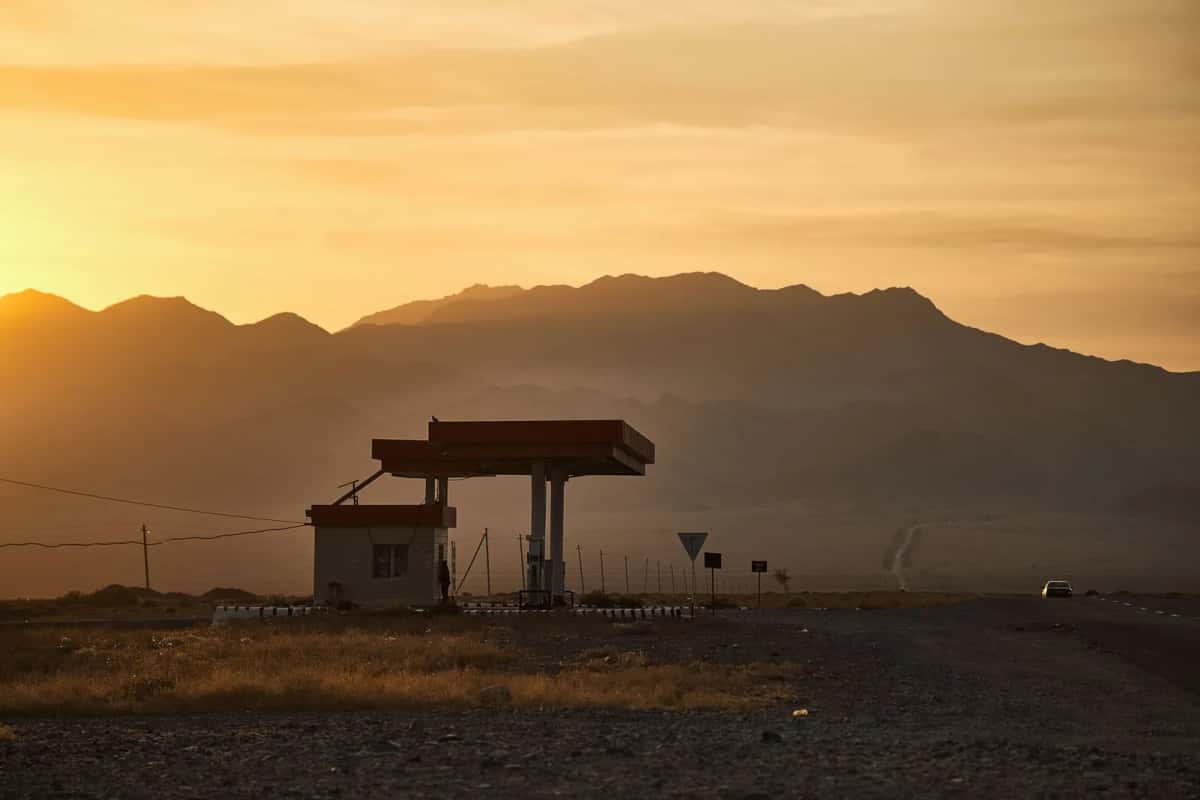 Station-service isolée au bord d'une route, devant une chaîne de montagnes au crépuscule