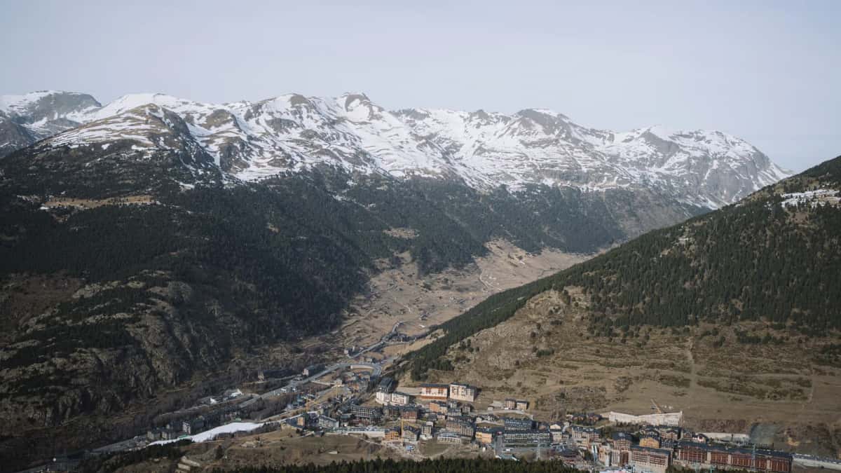Une vallée andorrane au fond dénudé et sans neige, dominée par des crêtes entièrement enneigées