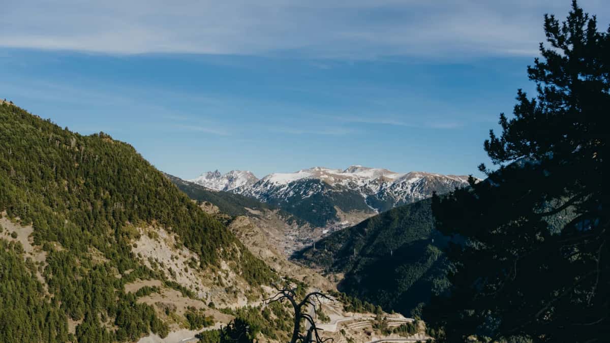 Vallée andorrane boisée et encaissée vue depuis un belvédère d'altitude, la route en lacets au fond